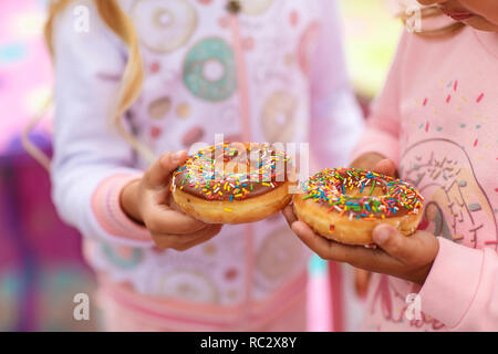 Deux filles sont maintenant un doux et un gros donut décoré de glaçage rose et vinaigrette de confiserie Banque D'Images