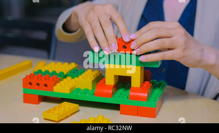 Close up shot of woman mains jouant avec des blocs de plastique en couleur constructeur Banque D'Images