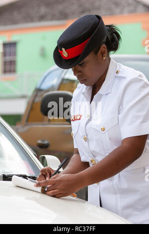 / Nassau Bahamas - Avril 3,2007 : Portrait d'un agent de la police des Bahamas femme vêtue de l'uniforme blanc et noir hat écrit le billet de stationnement. Banque D'Images