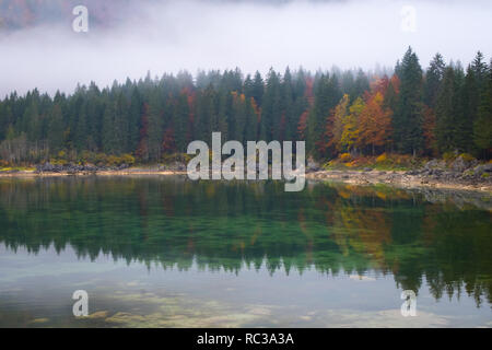 Belles réflexions de forêt colorée sur le lac Laghi di Fusine sur un matin brumeux en automne près de Tarvisio en Italie, Europe Banque D'Images