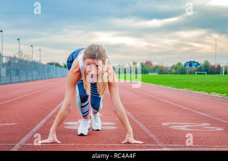 Jeune femme fitness en attente de début de course sur un stade. Banque D'Images