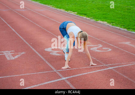 Jeune femme fitness en attente de début de course sur un stade. Banque D'Images