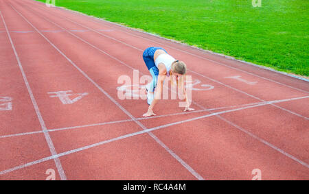 Jeune femme fitness en attente de début de course sur un stade. Banque D'Images