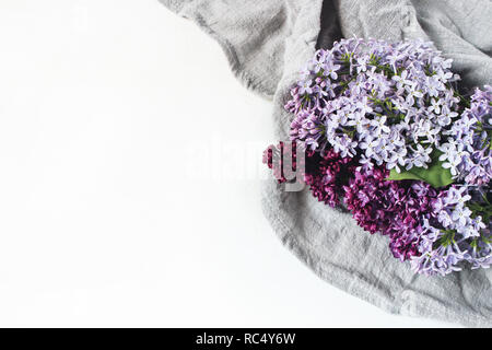 Style de pâques stock photo. La scène féminine de printemps, composition florale. Bannière décorative, faite de beau coin fleurs lilas pourpre sur lin serviette. Arrière-plan du tableau blanc. Mise à plat, vue du dessus. Banque D'Images