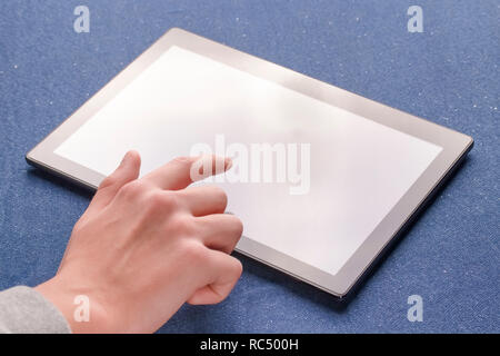 Utiliser les mains une pièce lumineuse tablette noir sur une feuille de tissu bleu. Banque D'Images