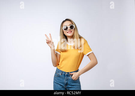 Young Asian woman wearing sunglasses sur fond isolés montrant et pointant vers le haut avec les doigts le numéro deux en souriant confiant et heureux. Banque D'Images