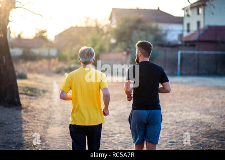 Les hommes courir dans le parc au coucher du soleil Banque D'Images