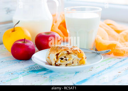 Des délicieux strudel aux pommes fait maison sur plaque blanche placés aux pommes et cannelle servi avec du lait en verre sur la vieille table en bois usés Banque D'Images
