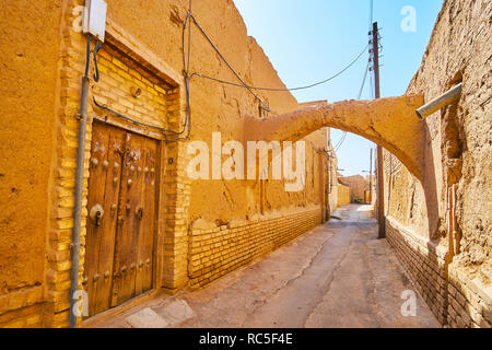 La vieille ville de rue minable avec porte en bois médiévale, la détérioration des murs en adobe, courbe kuche et passage route étroite, Yazd, Iran. Banque D'Images
