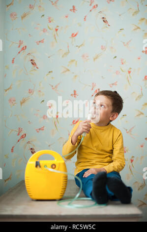 Petit caucasien enfant faire inhalation avec à la maison nébuliseur Banque D'Images