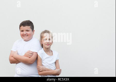 Heureux mignon jeune garçon épais d'épaule à épaule avec très mince petit jolie fille en chemise blanche avec copyspace Banque D'Images