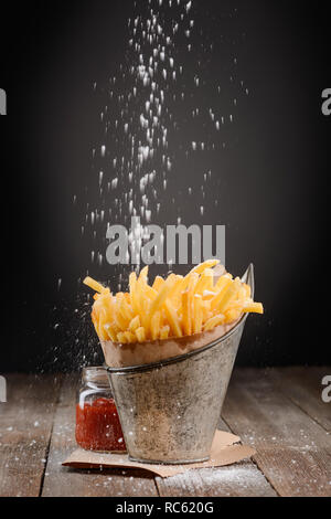 Saupoudrer de sel sur les frites Banque D'Images