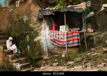 Haridwar / INDE - Août 2011 : Un homme assis sur les marches en pierre en face d'un petit autel hindou Banque D'Images