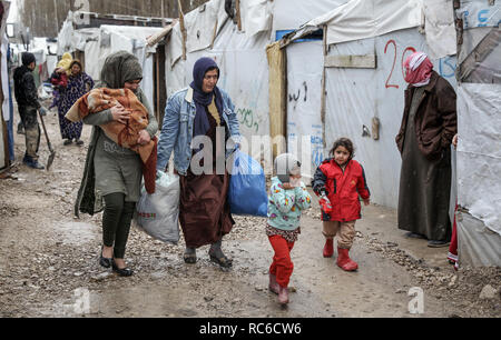 13 janvier 2019, au Liban, les réfugiés syriens : Barelias à pied le long d'une allée boueuse entre leurs tentes au milieu de temps froid à l'Barelias camp de réfugiés. Cinq jours de tempête la semaine dernière ont dévasté des milliers de camps de réfugiés syriens, et ils sont maintenant préparent à une autre grosse tempête dans les prochains jours. Photo : Marwan Naamani/afp Banque D'Images