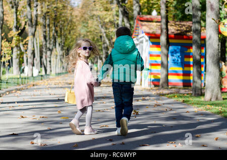 Jolie petite fille et garçon, 6 ans de marche à travers le parc. Les amis se tenant la main. Banque D'Images