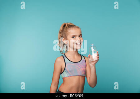 Happy little girl portant des vêtements de sport d'eau potable d'une bouteille isolé sur fond bleu Banque D'Images