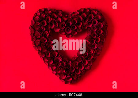 Coeur en roses rouges sur fond rouge pour la Saint-Valentin. Banque D'Images