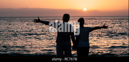 Valentine's day concept avec couple en silhouette bénéficiant de couleur rouge magnifique coucher ensemble les bras d'ouverture et d'avoir plaisir avec la nature outdoor leis Banque D'Images