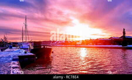 Scenic rouge violet et violet coucher de soleil sur la rivière campagne en Europe avec de vieux navires ayant reste à l'harfang harbour pier Banque D'Images