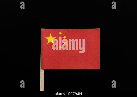 Un unique et simple pavillon de la Chine sur les cure-dents sur fond noir. Une grande étoile d'or dans un arc de quatre petites étoiles d'or, dans le canton, sur Banque D'Images
