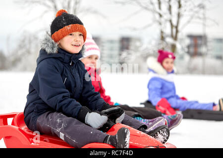 Happy kids glissant sur les traîneaux en hiver Banque D'Images