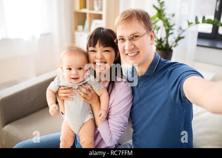 Mixed Race family avec bébé en tenant à la maison selfies Banque D'Images