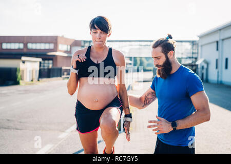 Femme enceinte et entraîneur personnel travaillant à l'extérieur Banque D'Images