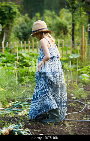 Girl in blue dress walking through field Banque D'Images