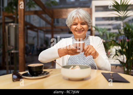 Senior woman photographing food at street cafe Banque D'Images