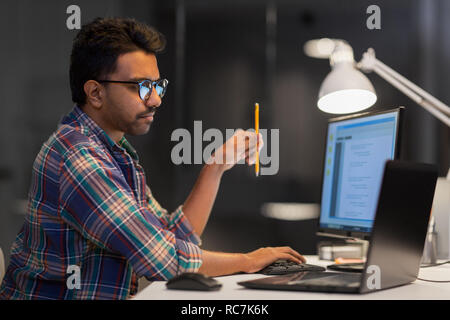 L'homme créatif travaillant avec un ordinateur portable à l'office de nuit Banque D'Images