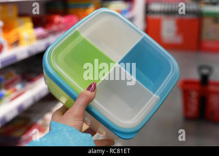 Conteneur alimentaire en plastique dans la main sur fond boutique femme Banque D'Images