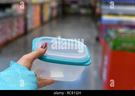 Conteneur alimentaire en plastique dans la main sur fond boutique femme Banque D'Images