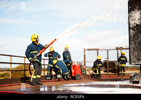 Formation des Pompiers Pompiers Pompiers, la pulvérisation de mousse à l'établissement de formation Banque D'Images