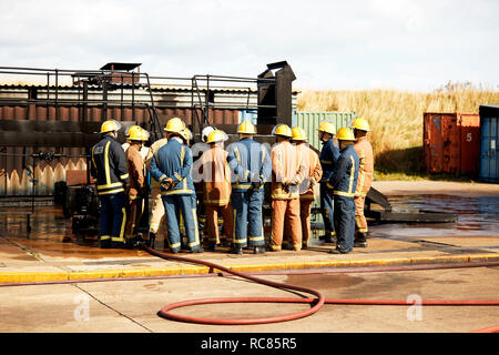 La formation des pompiers, de l'équipe de pompiers volontaires à l'écoute de superviseur au centre de formation, vue arrière Banque D'Images