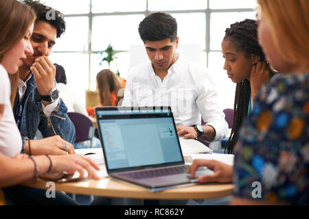Les hommes et les étudiants de l'enseignement supérieur et travail d'équipe using laptop in college classroom Banque D'Images
