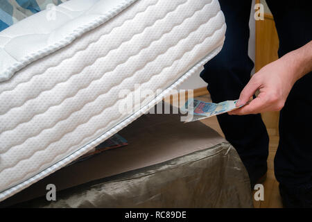 L'homme de mettre l'argent sous son matelas pour l'enregistrer. Ne montrant aucune confiance dans les institutions financières et les banques, marché noir Banque D'Images