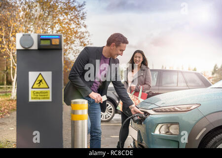 L'homme et la femme à la voiture électrique de charge charge voiture Park, Manchester, UK
