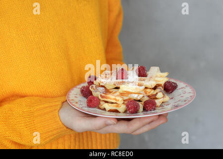 Des gaufres fraîchement préparées avec des framboises dans girl's hands Banque D'Images