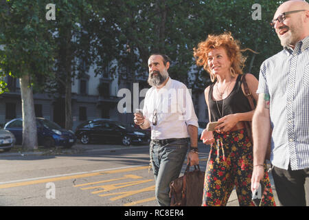 Mid adult woman and male friends chatting en flânant sur les trottoirs de la ville Banque D'Images