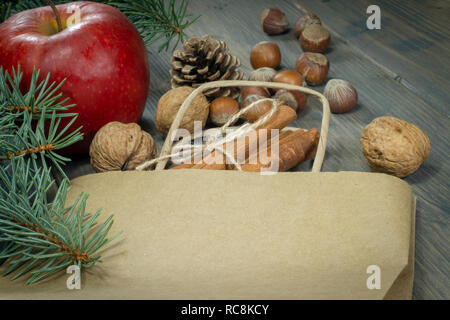 Divers les noix, la cannelle et la pomme en tant que concept de maison de l'épicerie, les étendre sur une table en bois plus de papier sac de shopping, vue en gros plan d'un Banque D'Images