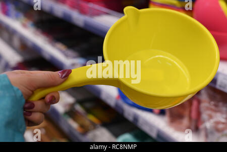 Seau en plastique pour l'eau dans la main sur fond boutique femme Banque D'Images