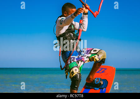 L'Egypte, Hurghada - 30 novembre, 2017 : vue latérale du kitesurfer debout sur la planche tenue le cerf-volant sangles. Extraordinaire mer Rouge et le fond de ciel bleu. Le professionnel de kitesurf. Banque D'Images