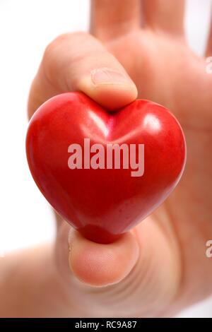 Main tenant un cœur rouge, image symbolique de la maladie cardiaque, crise cardiaque, un coeur malade, Cardiologie Banque D'Images