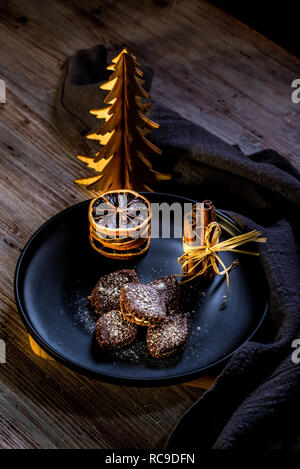 Photo verticale de plusieurs brown des bonbons. Les sucreries sont farcies de crème, couverts par chocolat et parsemé de noix de coco blanc de jetons. Quelques bâtons de cannelle et s Banque D'Images