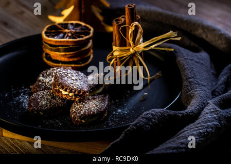 Photo horizontale de plusieurs brown des bonbons. Les sucreries sont farcies de crème, couverts par chocolat et parsemé de noix de coco blanc de jetons. Quelques bâtons de cannelle et Banque D'Images