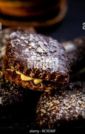 Photo verticale de plusieurs brown des bonbons. Les sucreries sont farcies de crème, couverts par chocolat et parsemé de noix de coco blanc de jetons. Quelques bâtons de cannelle et s Banque D'Images