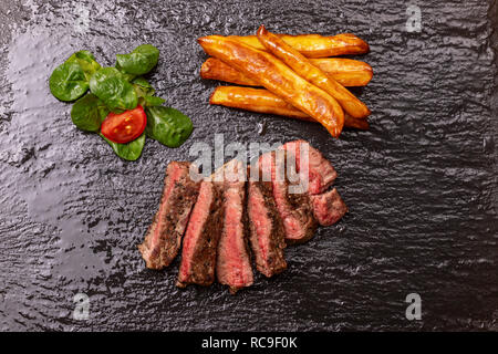 Tranches de steak avec des frites sur ardoise Banque D'Images