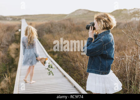 Young woman photographing ami sur la promenade de dunes côtières, Menemsha, Martha's Vineyard, Massachusetts, USA Banque D'Images