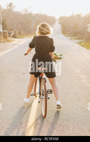 Young woman riding bicycle on rural road, vue arrière, Menemsha, Martha's Vineyard, Massachusetts, USA Banque D'Images