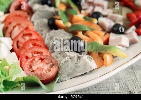 Un plat populaire de la cuisine américaine - salade Cobb, composé de légumes verts, oeufs, tomates, fromage, viande, produits empilés en rangées sur un large plat et poure Banque D'Images